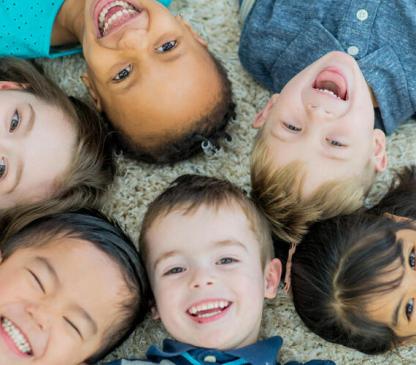 Group of children laying on their backs and smiling at camera