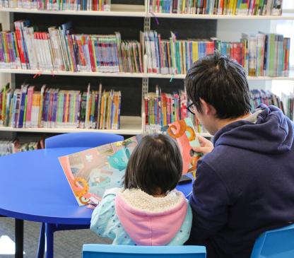 Man and child reading a picture book together in a library