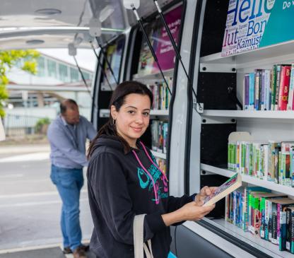 Person picking a book off a shelf of a mobile library