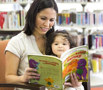 Woman holding a baby and reading a book together