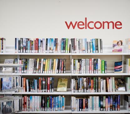 books on a shelf with a welcome sign above