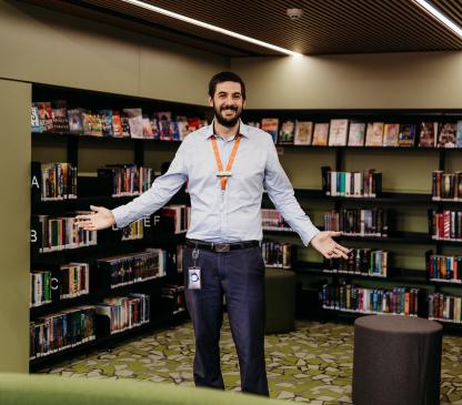 Man standing in the middle of a room with bookshelves