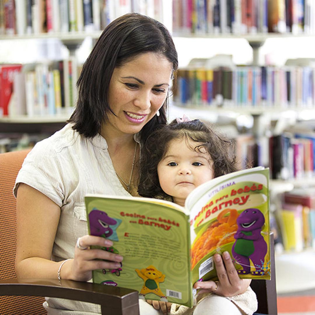 Woman holding a baby and reading a book together