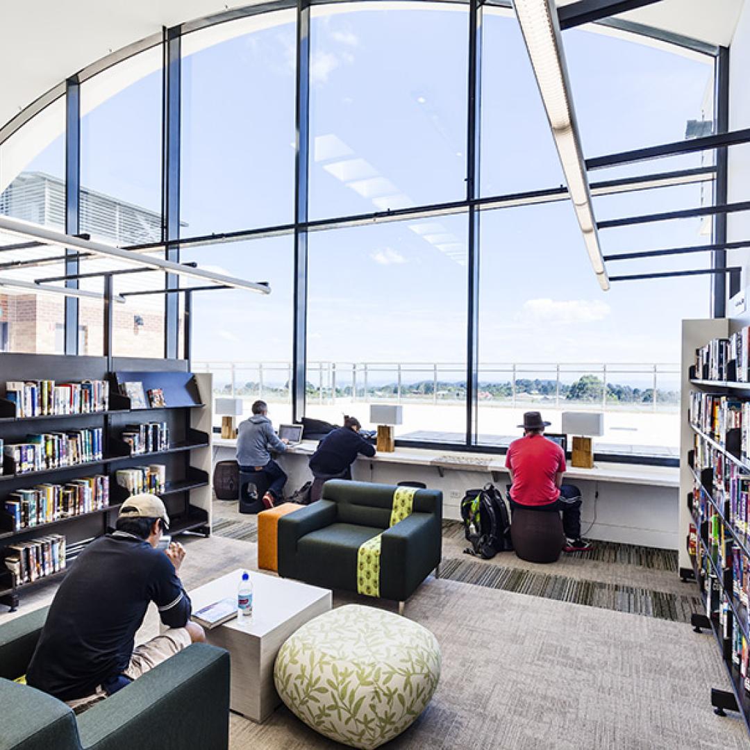 People sitting in a library with bookshelves
