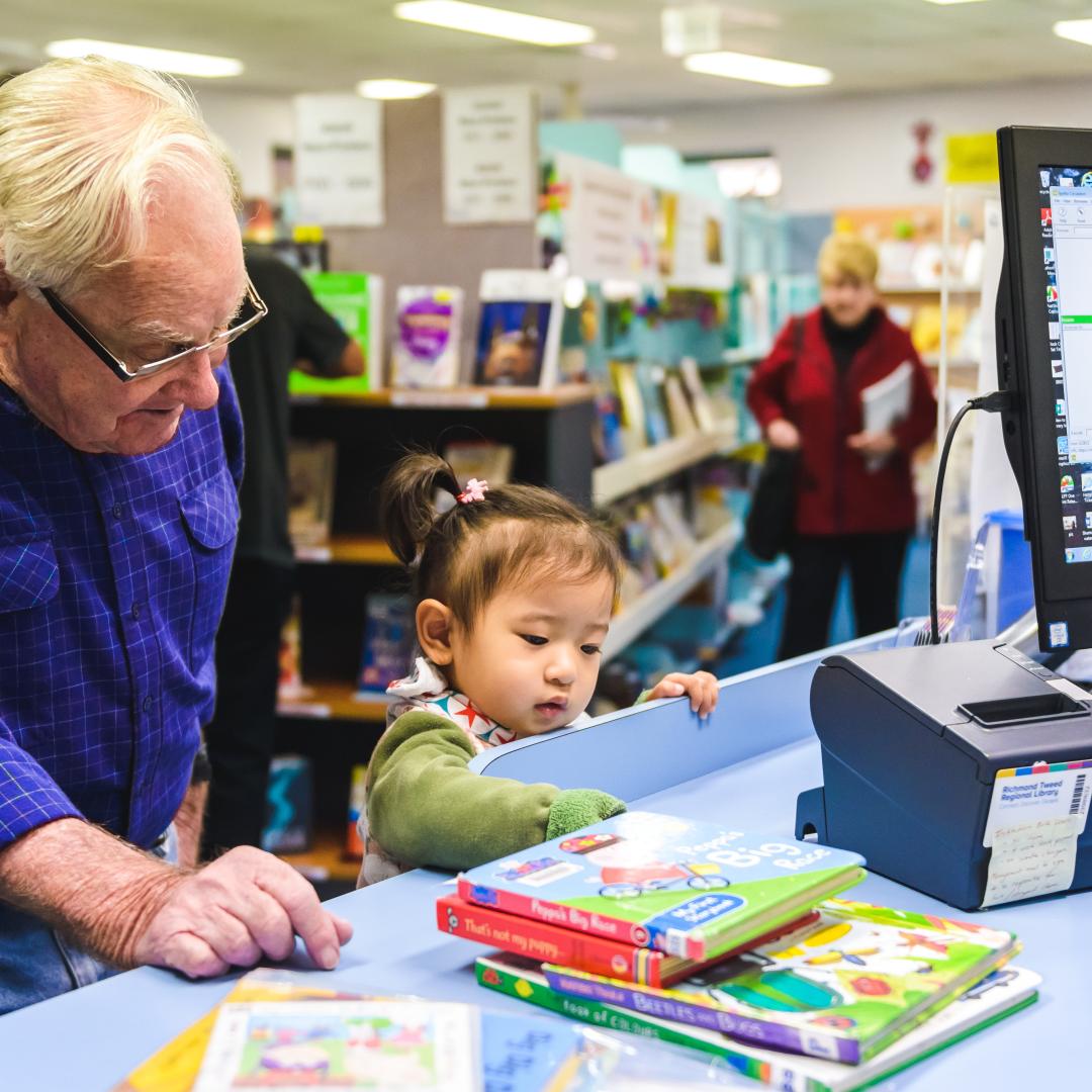 Older male and small child at a library service counter